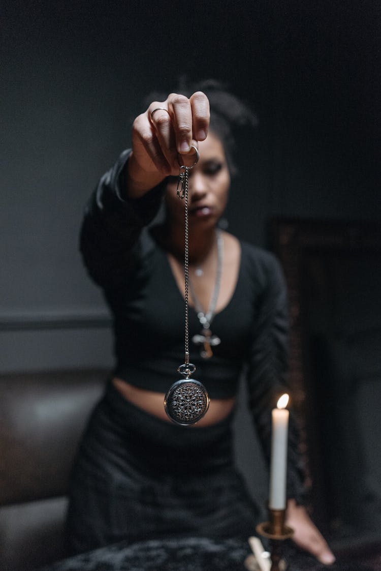 Woman Holding A Silver Necklace With A Round Pendant