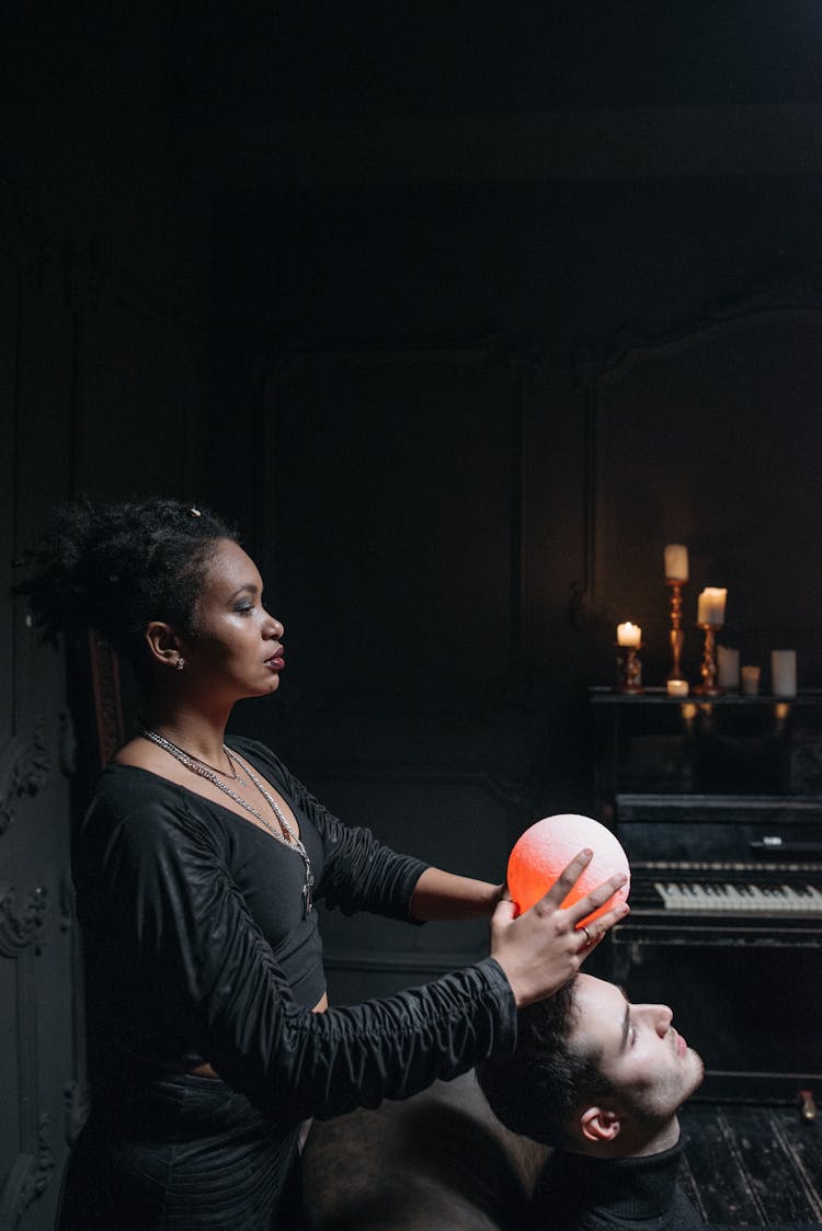 A Woman In Black Long Sleeves Holding A Ritual While Holding Crystal Ball