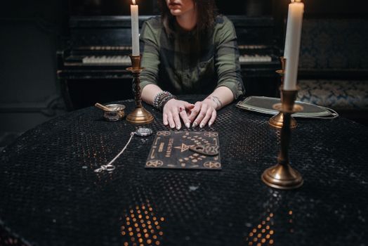 Woman Sitting at a Table with Ouija Board and Candles on it