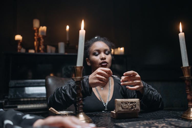 Woman Wearing Black Sitting In A Dark Room With Candles