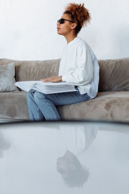 Free A blind woman reading a braille book while sitting on a sofa indoors. Stock Photo