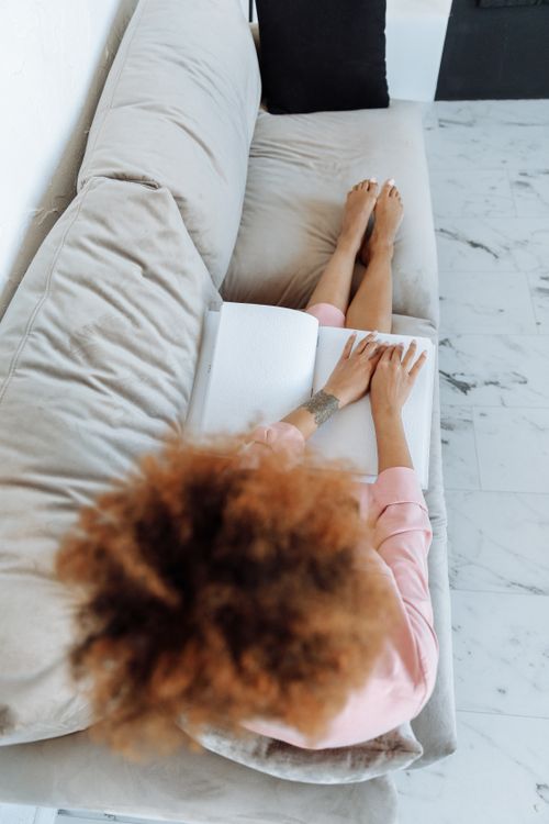Free Young woman reading a Braille book while relaxing on a sofa, promoting independence and leisure. Stock Photo