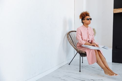 Free Blind woman in pink dress reading a Braille book while sitting indoors. Stock Photo