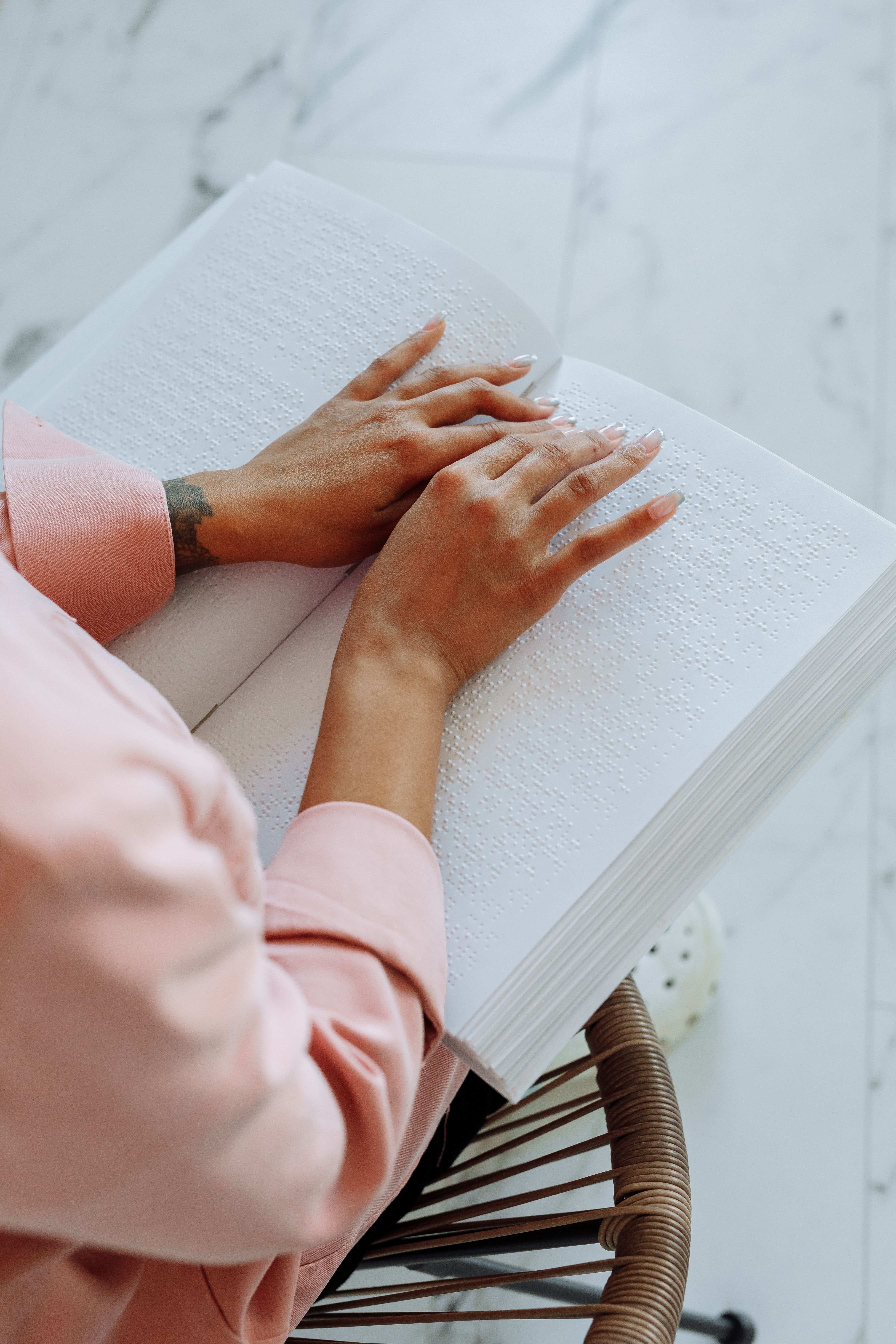 Close-up of hands reading a Braille book, symbolizing accessibility for the visually impaired.