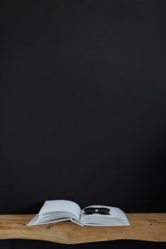 Minimalist still life of an open book and sunglasses on a wooden surface, ideal for background or design space.