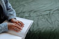 Person in Blue Long Sleeve Shirt Holding White Book