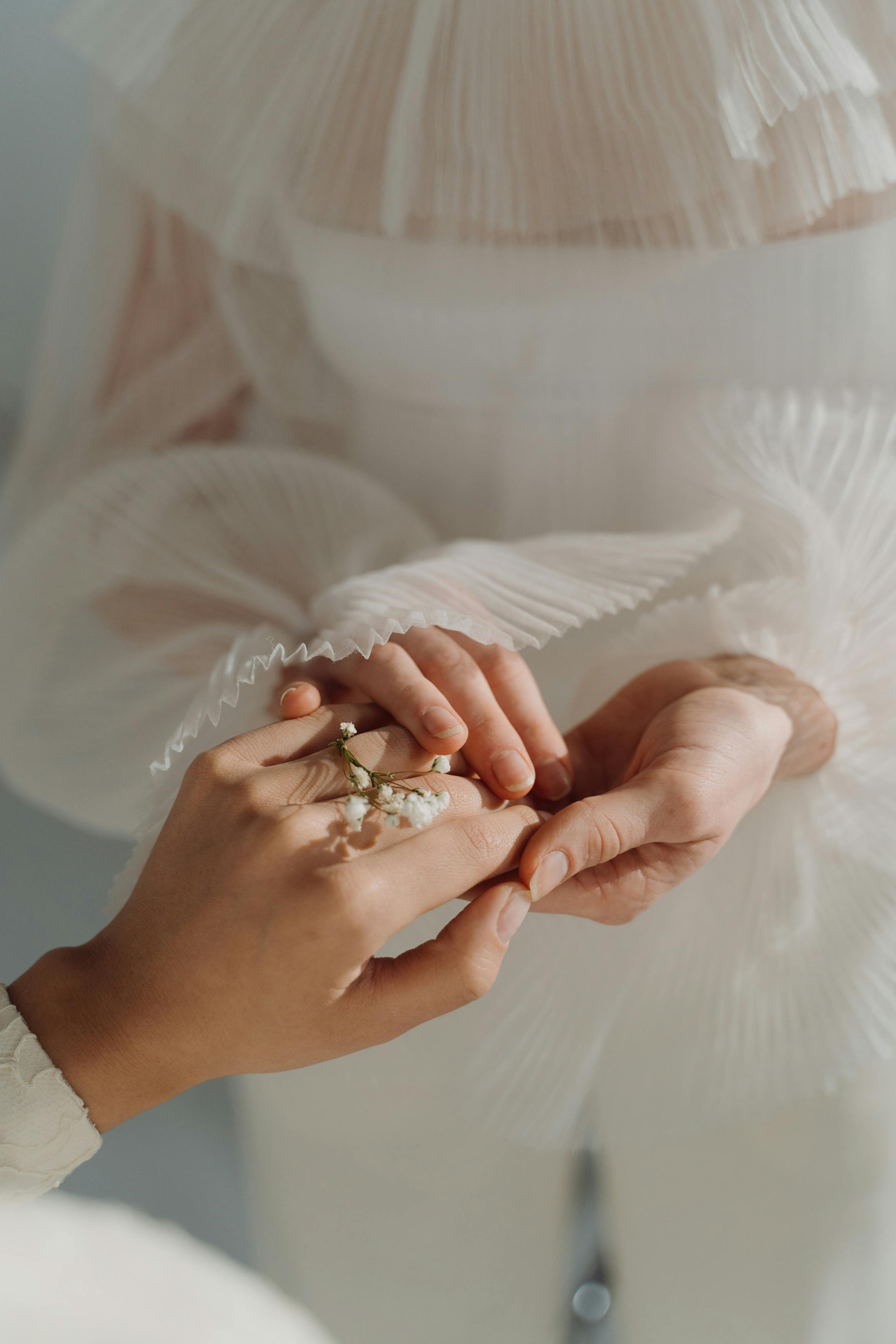 A close-up of women in elegant white dresses holding a delicate flower bouquet, symbolizing grace and connection.