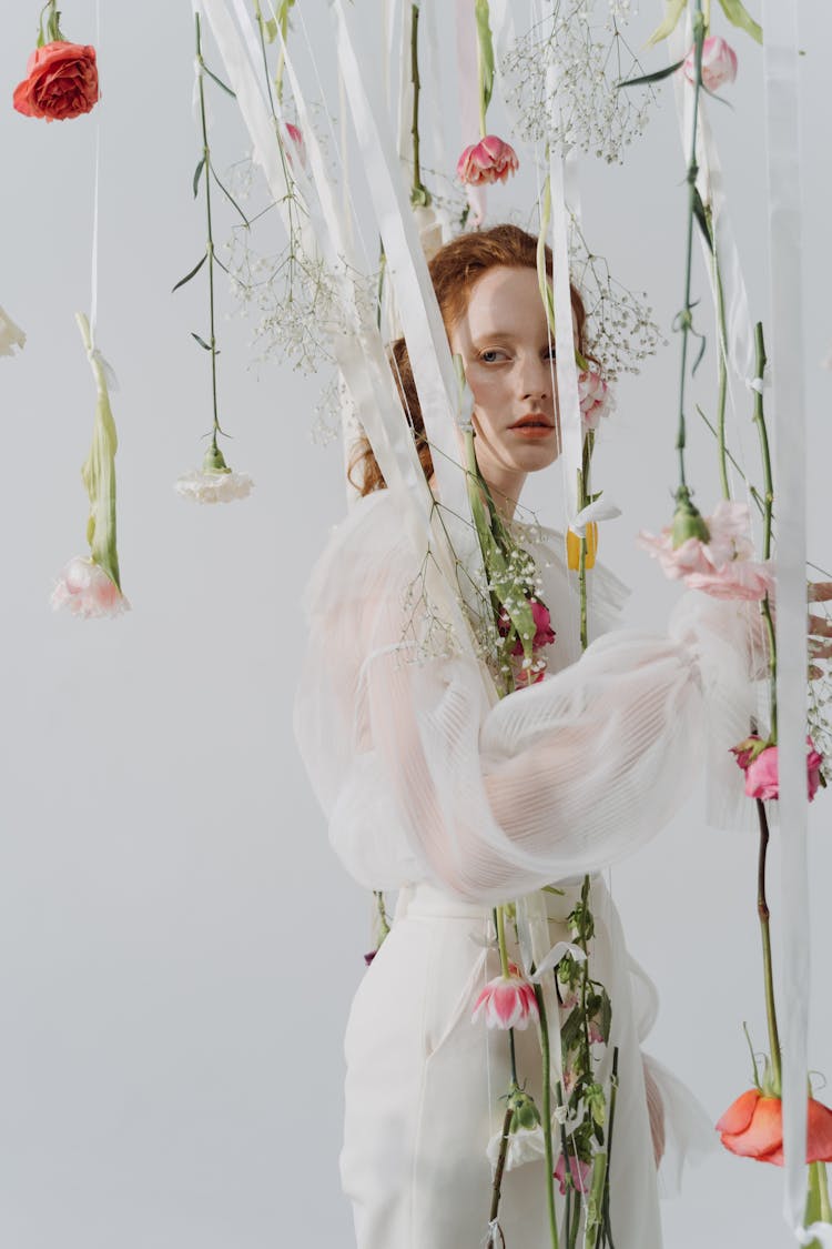 Redhead Woman Wearing A White Dress Posing With Floral Installation