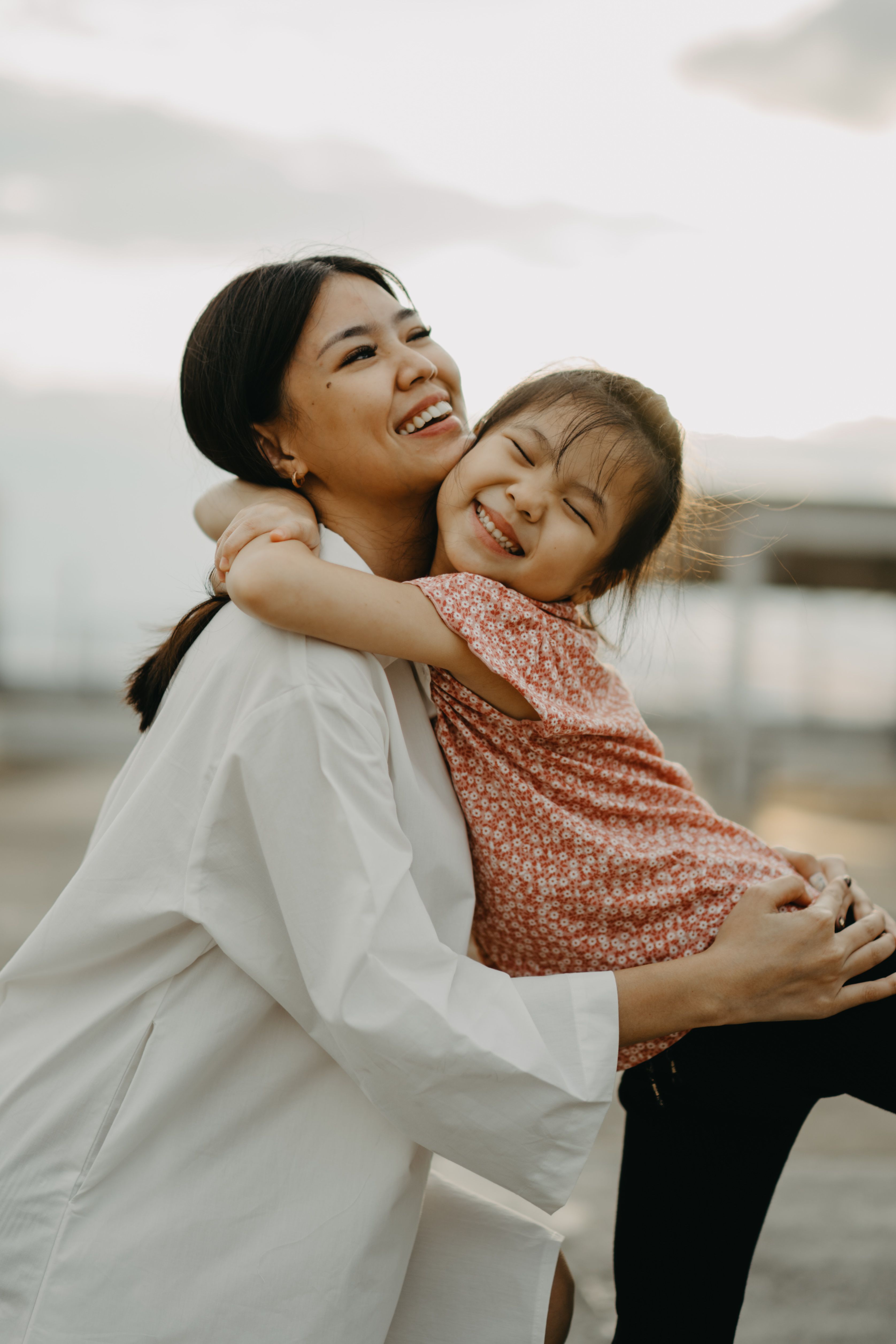 A heartwarming outdoor moment capturing a mother and daughter embracing with joy and warmth.