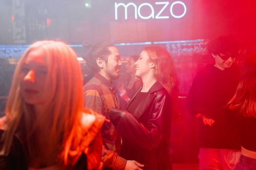 Man in Red Suit Jacket Standing Beside Woman in Black Coat