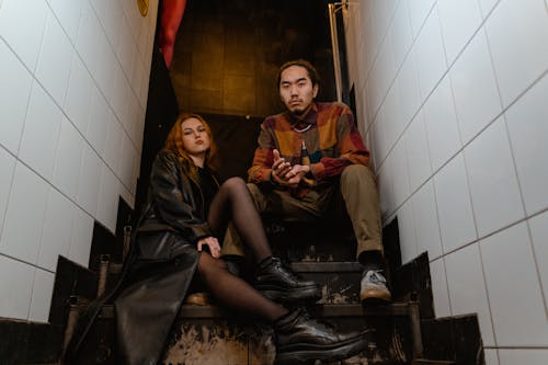 Low-Angle Shot of Man and Woman Sitting on Stairs