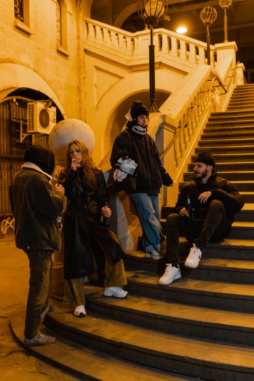 Free Four friends enjoying a casual night out with drinks and conversation on urban stairs. Stock Photo