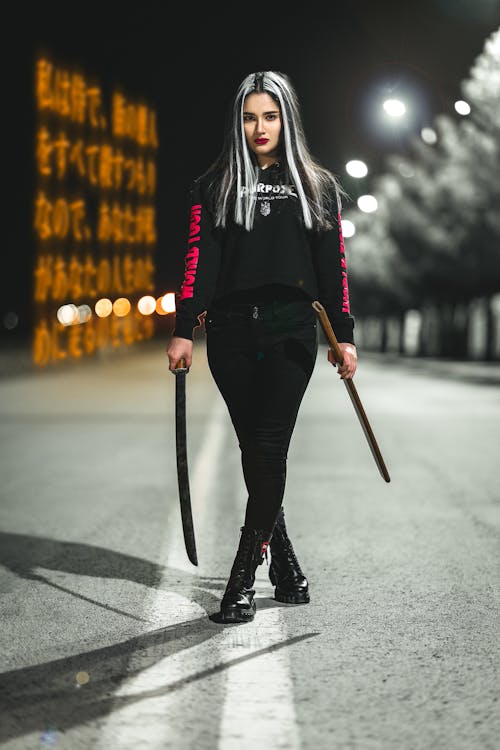 Free Photo of a Woman in a Black Hoodie Holding a Sword Stock Photo