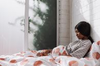 Man in Gray and White Plaid Dress Shirt Sitting on Bed