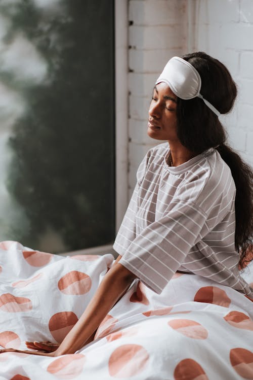 Free Girl Sitting in Bed with a Sleep Mask on her Forehead Stock Photo