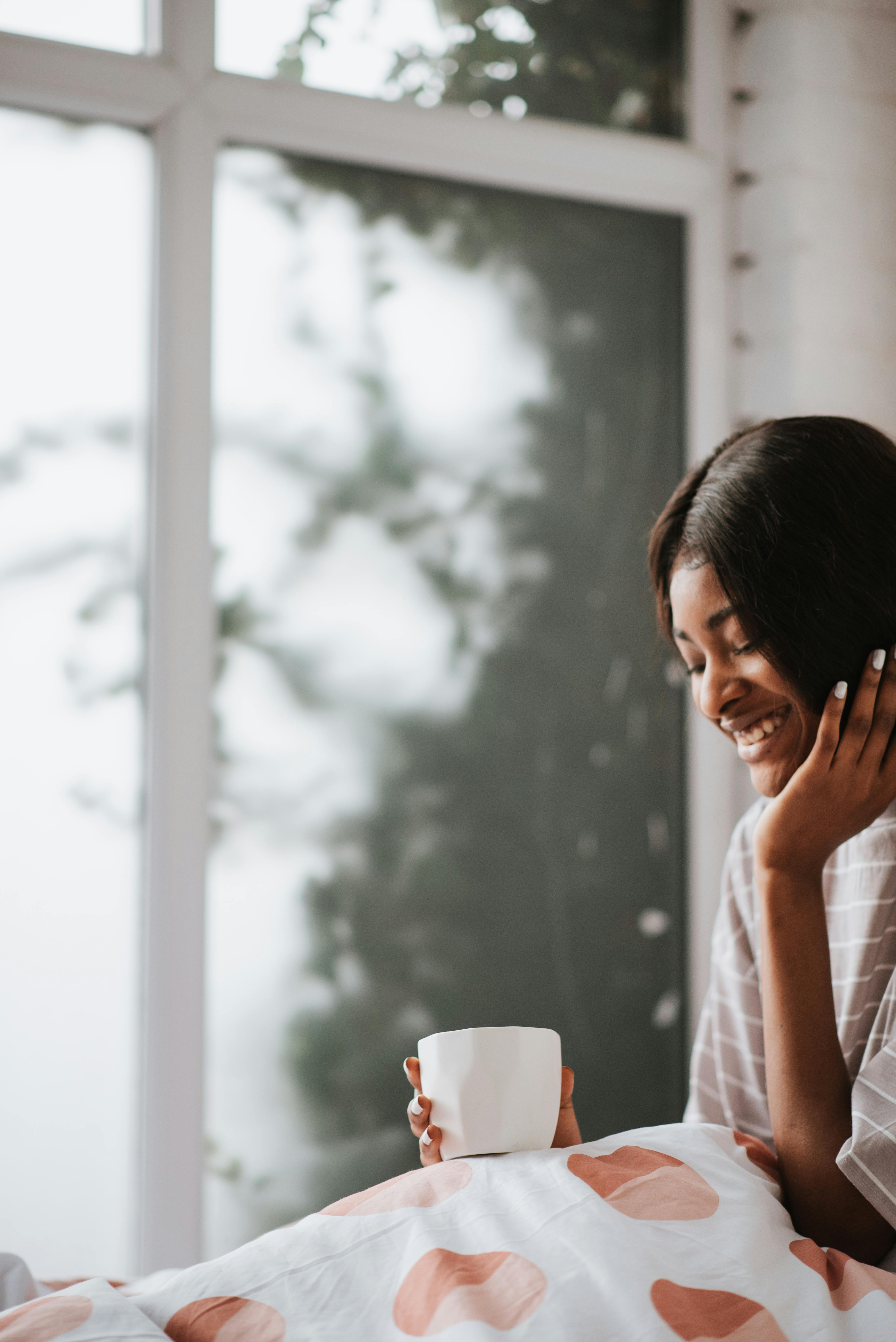 a smiling woman holding a cup of coffee