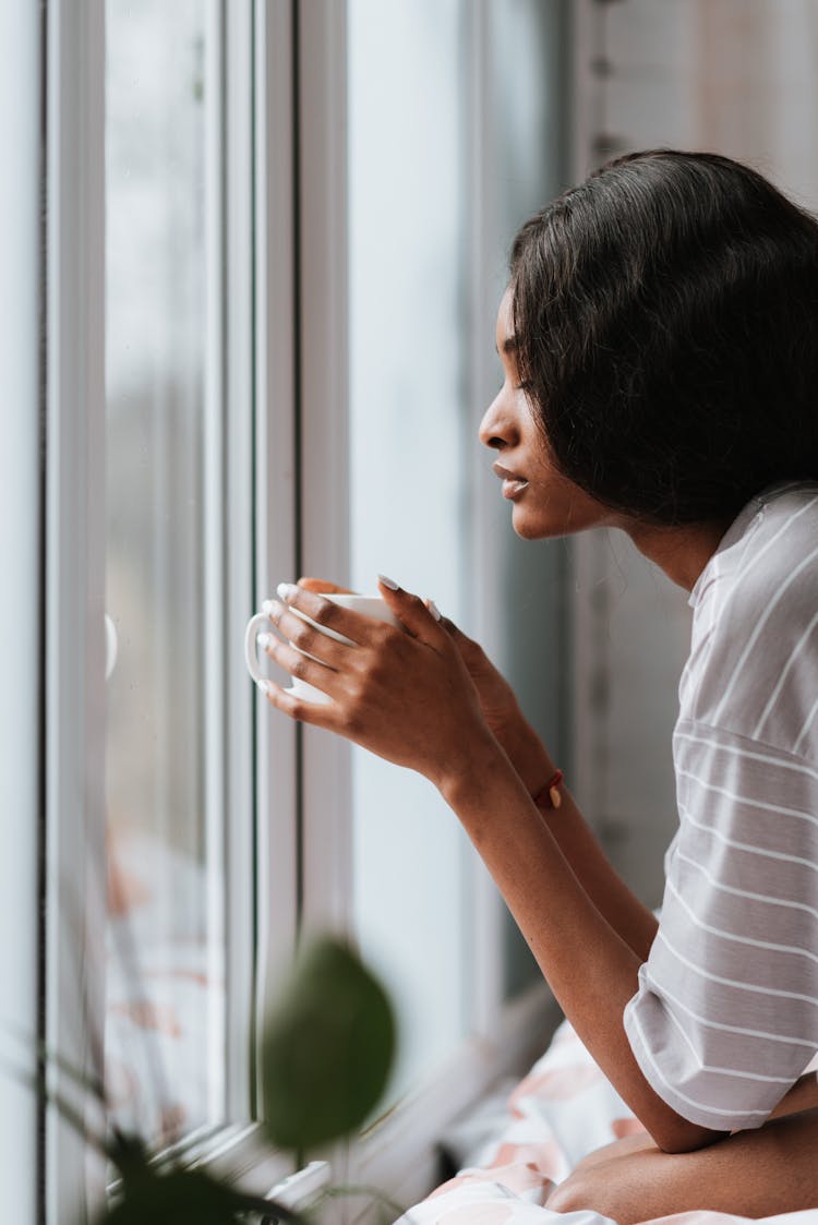 A Side View Of A Woman In Striped Shirt Holding A Cup Of Coffee