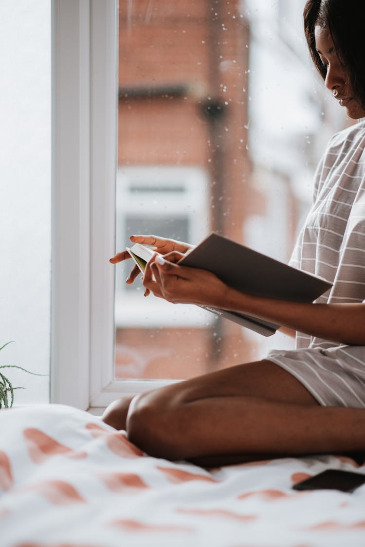 Woman In Pyjama Sitting In Bed Reading Book