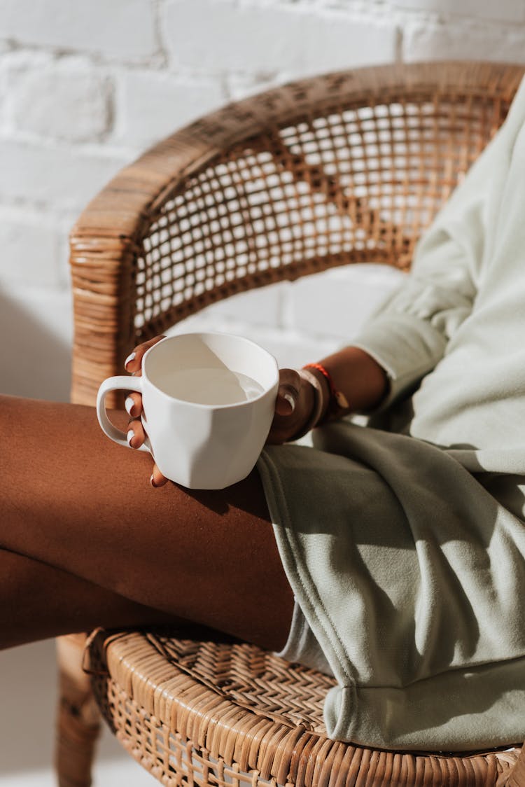 Crop Ethnic Woman With Cup Of Water Resting In Armchair