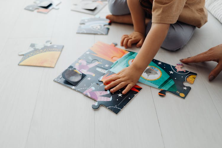 A Kid's Hands Solving A Jigsaw Puzzle