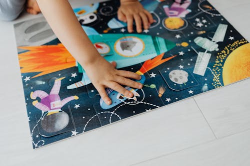 Close-Up Photo of a Child's Hands Solving a Jigsaw Puzzle