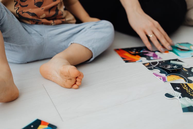 A Child Sitting On The Floor With A Jigsaw Puzzle