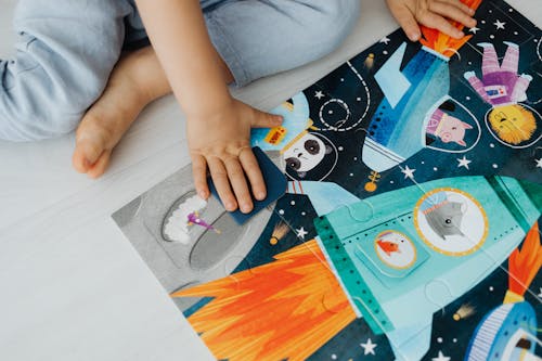 Photograph of a Kid's Hands Solving a Jigsaw Puzzle