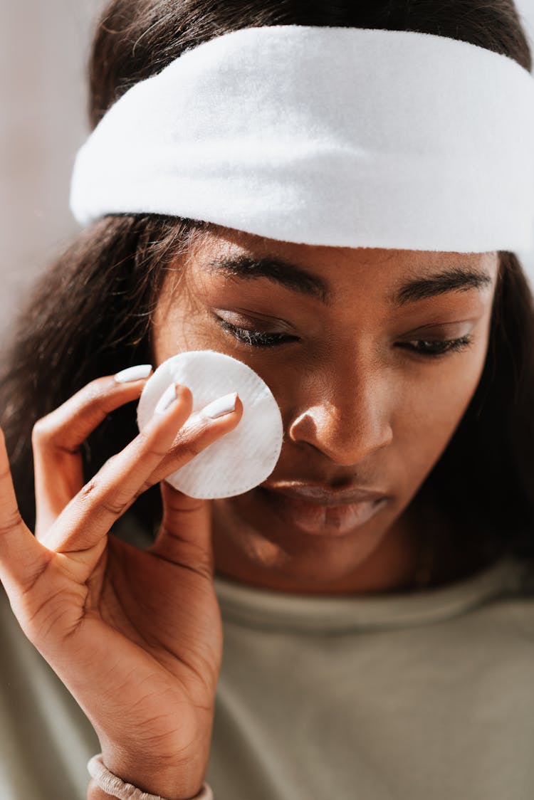 Black Woman Cleaning Face With Cotton Pad In Sunshine