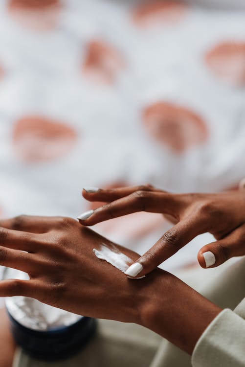 Crop black woman applying nourishing cream on hand