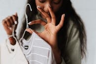 Crop young African American female with wear on hangers demonstrating good gesture on light background