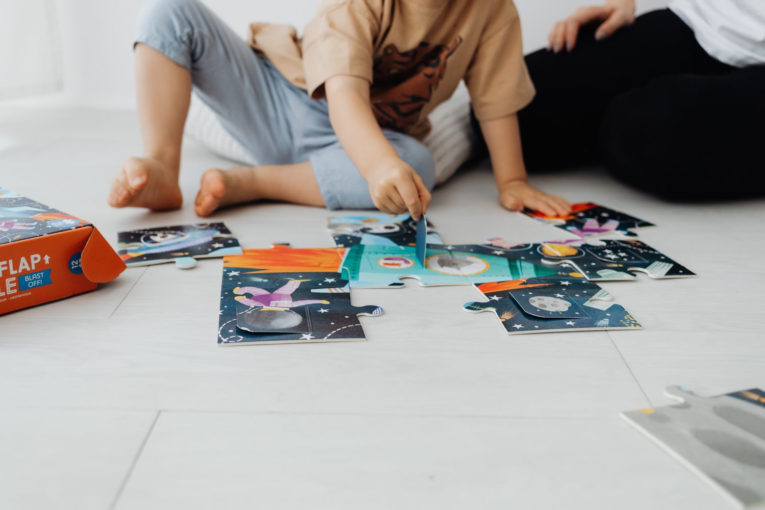 Two children working together to complete a colorful floor puzzle
