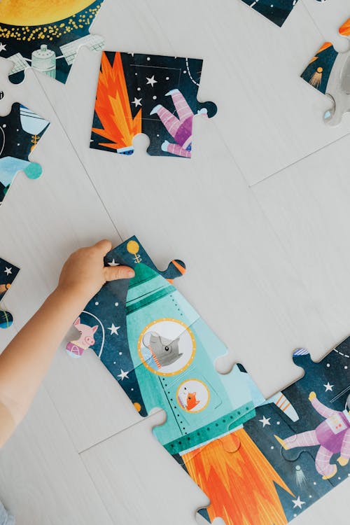 Photograph of a Kid Solving a Jigsaw Puzzle on the Floor