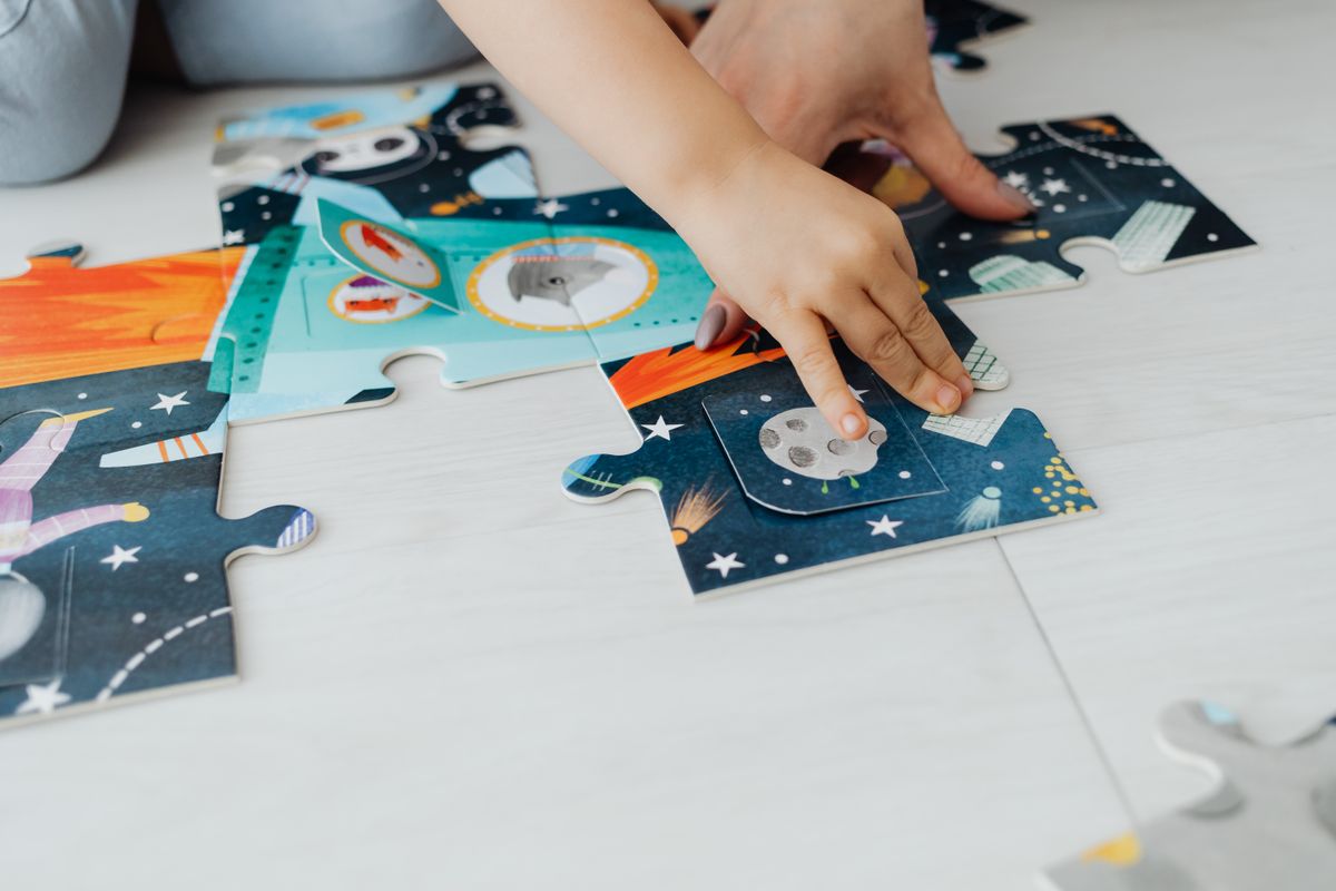 A child's hand solving a jigsaw puzzle