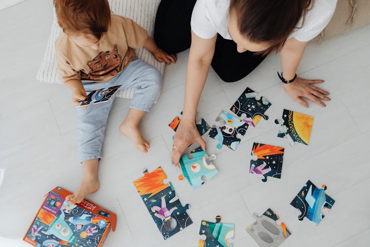 Top View Of Woman With A Child Solving Puzzles