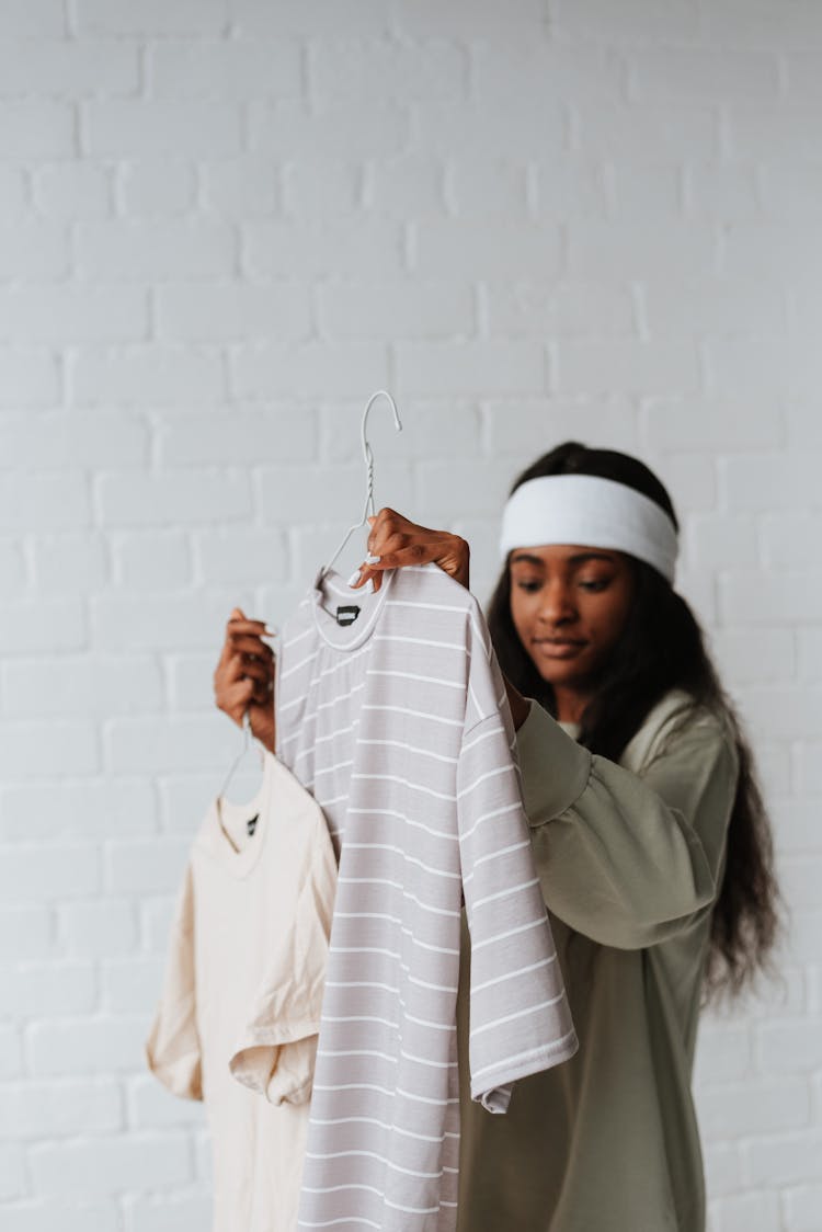 Ethnic Woman Choosing T Shirts On Hangers On White Background