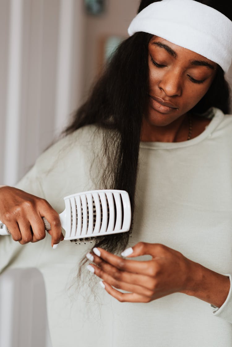 Crop Black Woman Combing Long Hair At Home