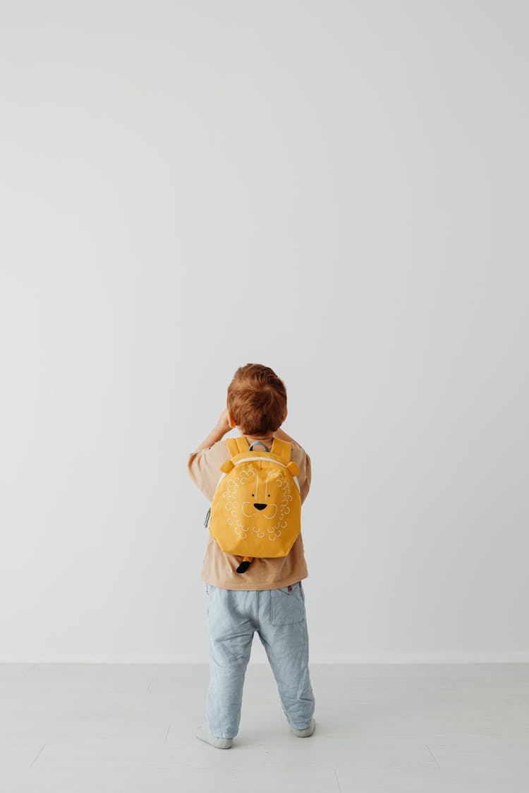 Child With Backpack In White Studio Background