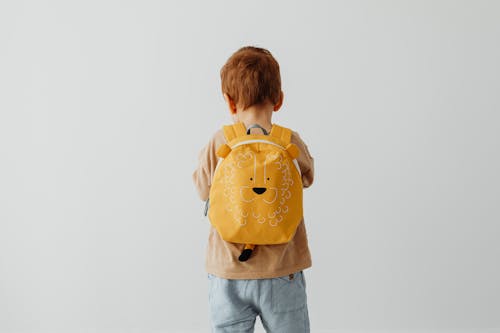 Back View of a Boy in a Brown Shirt Wearing a Yellow Backpack