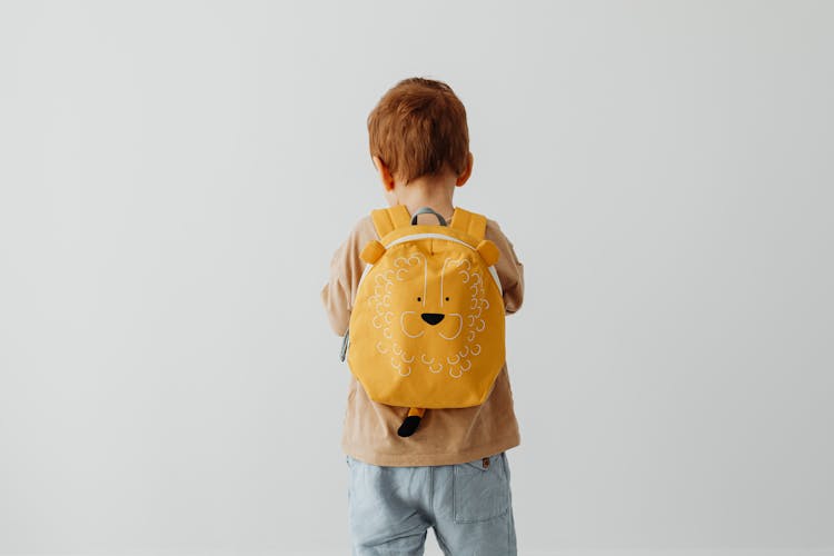 Back View Of A Boy In A Brown Shirt Wearing A Yellow Backpack