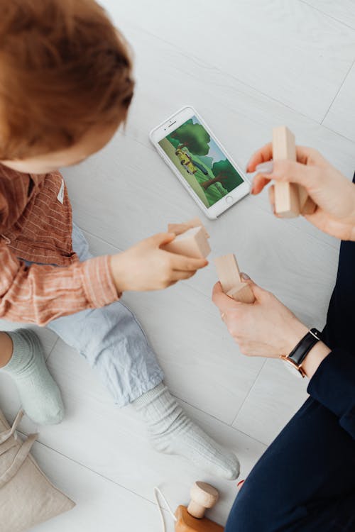 Free Child and Mother with Cellphone and Toy Blocks Stock Photo