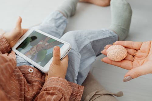 A Kid Holding a Cell Phone Near a Person's Hand