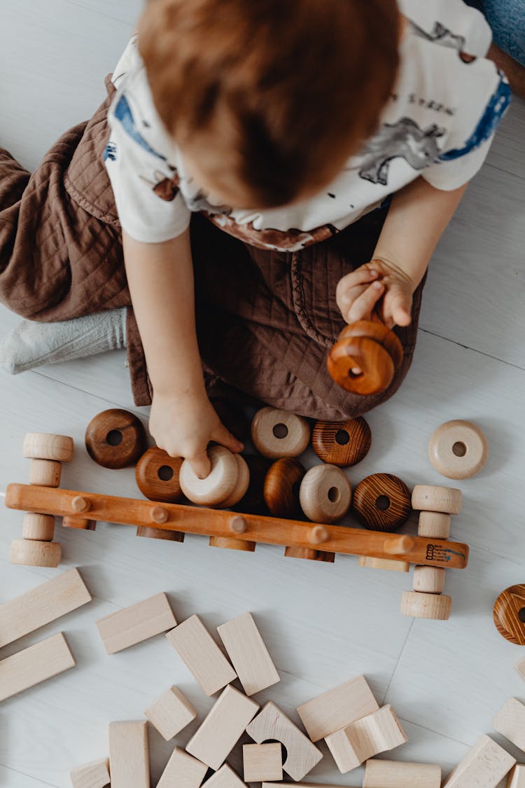 Overhead Shot Of A Boy Playing With Wooden Toys