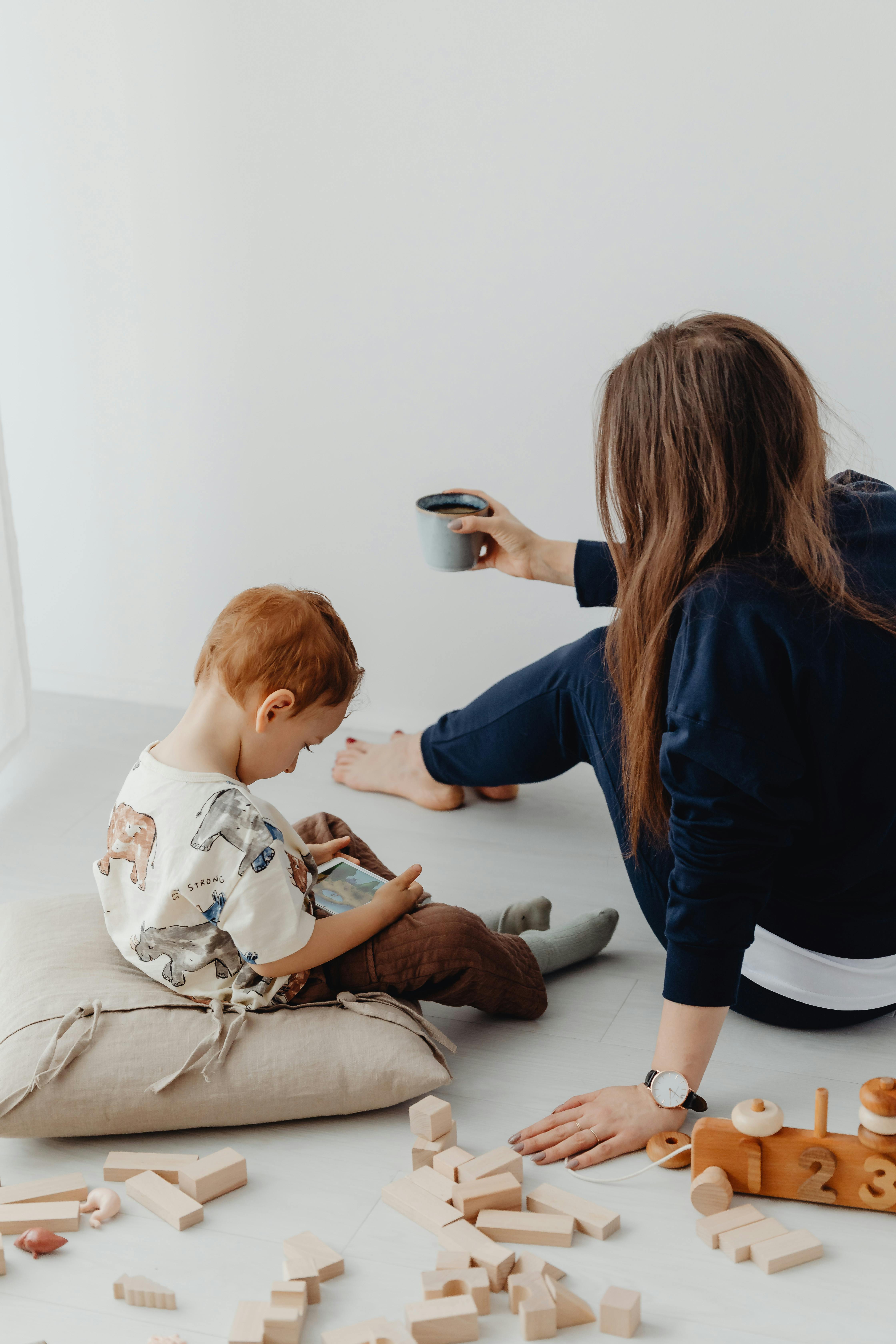 a boy watching on a cell phone near his mother