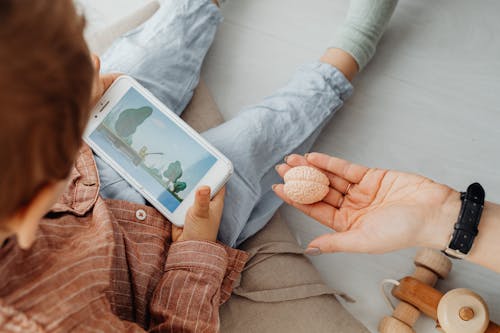 A Person's Hand Near a Kid Holding a Smartphone