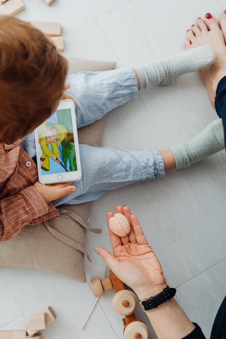 Overhead Shot Of A Kid Watching On A Cell Phone