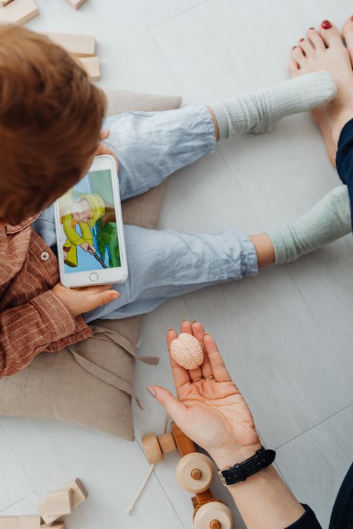 Free A child watching a video on a smartphone while adults supervise indoors. Stock Photo