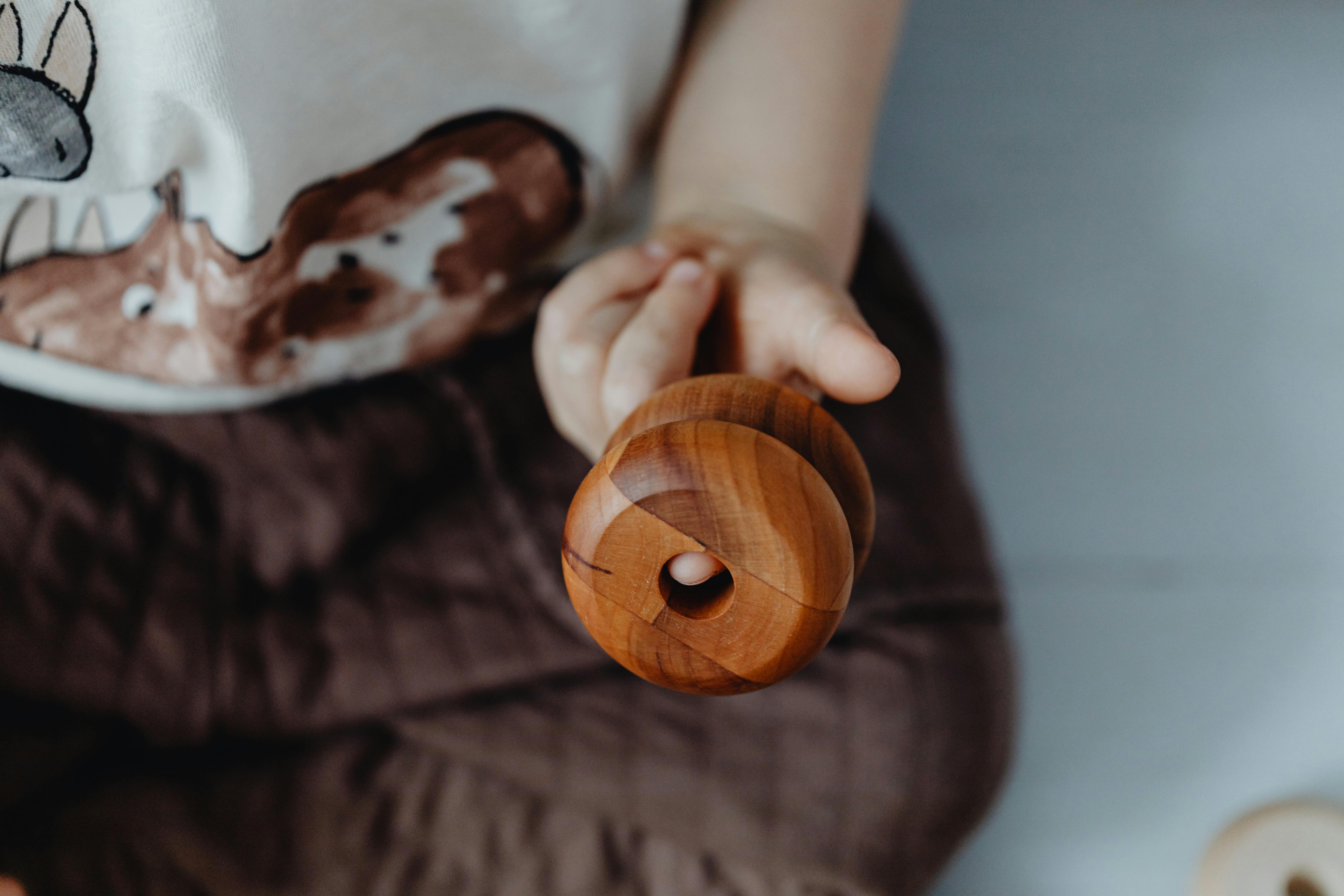 Environmental Impact of Choosing Eco-Friendly Toys: A close-up of a child holding a handcrafted wooden toy, emphasizing texture and detail.