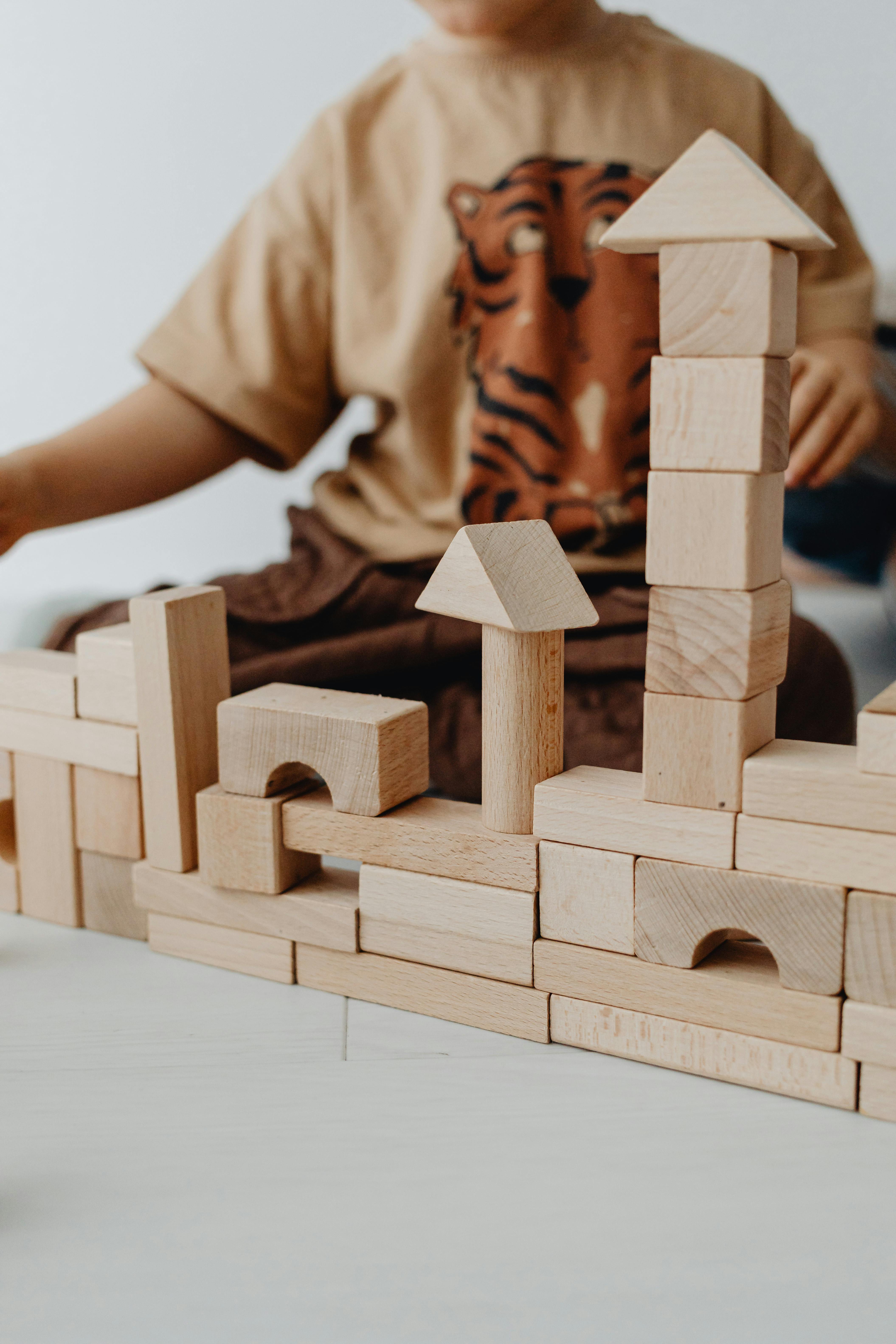 A child builds a structure with wooden blocks, encouraging creativity and learning.