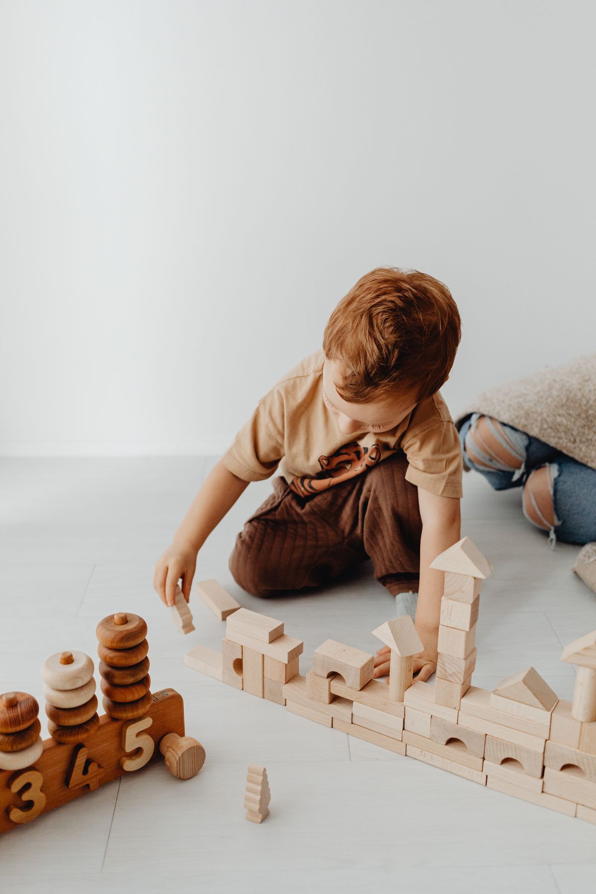Child carefully building a structure with wooden educational blocks