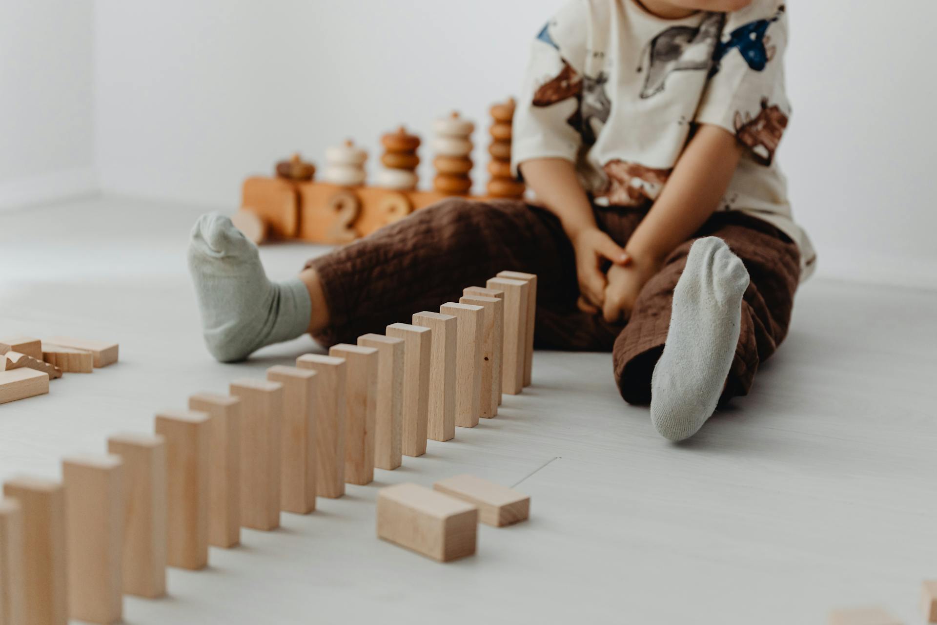 Photograph of a Kid Sitting Near Wooden Blocks